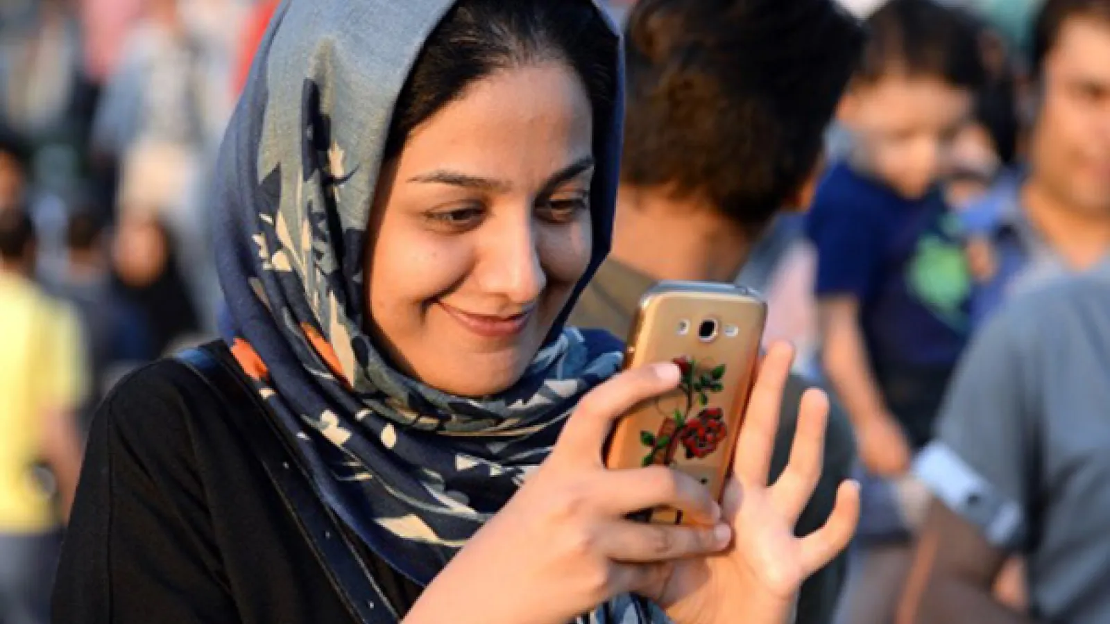 Picture of an Iranian girl smiling at her phone.