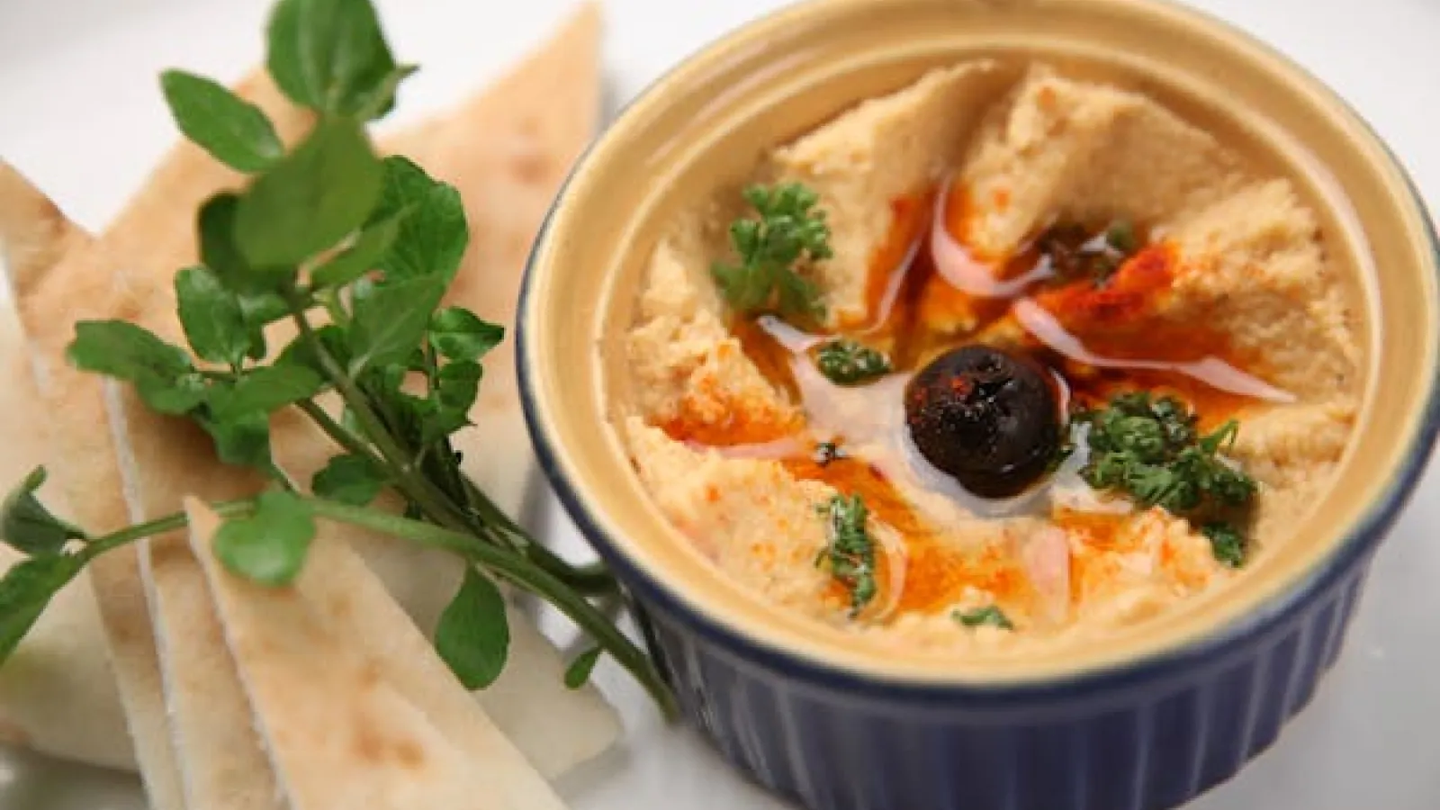 A side of hummus next to slices of pita bread