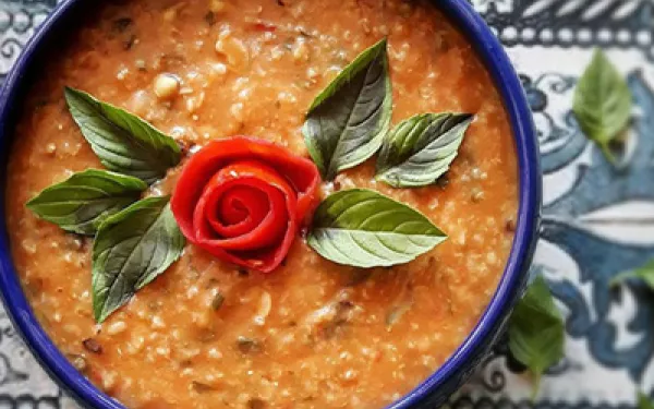 a bowl of ashe ab ghooreh garnished with herbs