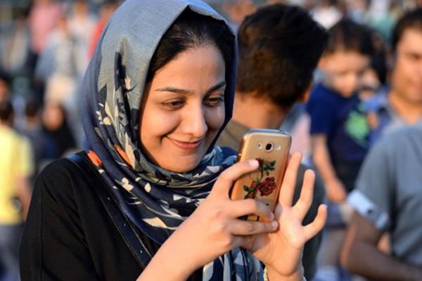 Picture of an Iranian girl smiling at her phone.